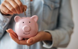 Person places money in a piggy bank to represent Stapled Super Fund Changes - Garnet Business Solutions Article